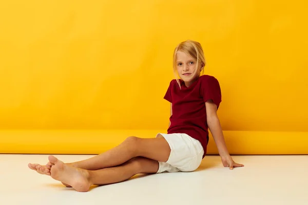 Küçük kız yerde oturmuş günlük kıyafetlerle poz veriyor. — Stok fotoğraf