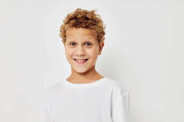 Kudrnatý chlapec v bílém tričku pózuje zábavné dětství v nezměněném stavu — Stock fotografie