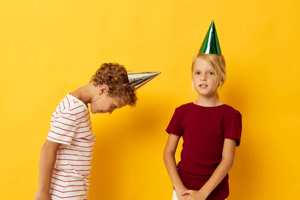 Симпатичные дошкольные дети праздник весело с шапками на голове желтый фон — стоковое фото
