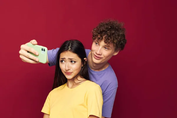 Bel ragazzo e ragazza in t-shirt colorate con un telefono Stile giovanile — Foto Stock