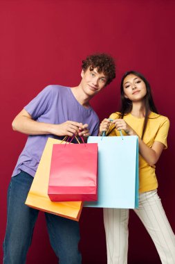 Gençler renkli çantalar alışverişte eğlenceli kırmızı arka plan değiştirilmemiş