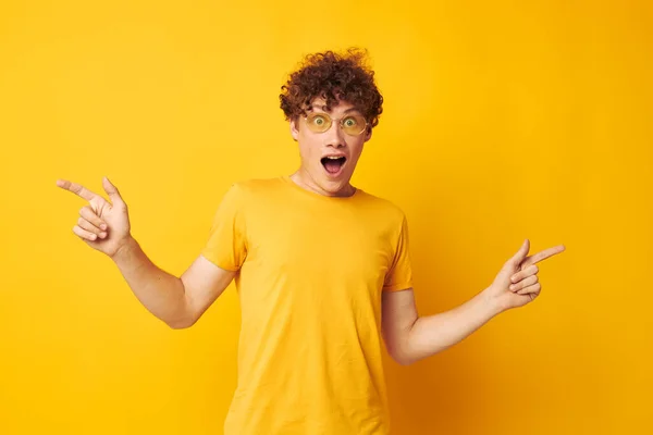 Portrait d'un jeune bouclé homme jaune t-shirt lunettes mode main gestes isolé fond inaltéré — Photo
