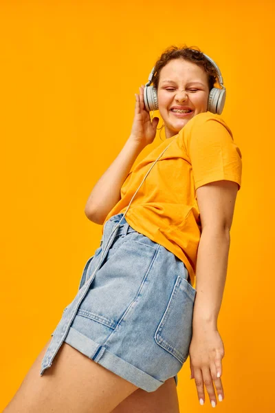 Όμορφη γυναίκα κίτρινο t-shirt ακουστικά ψυχαγωγία μουσική διασκέδαση απομονωμένα υπόβαθρα αμετάβλητη — Φωτογραφία Αρχείου