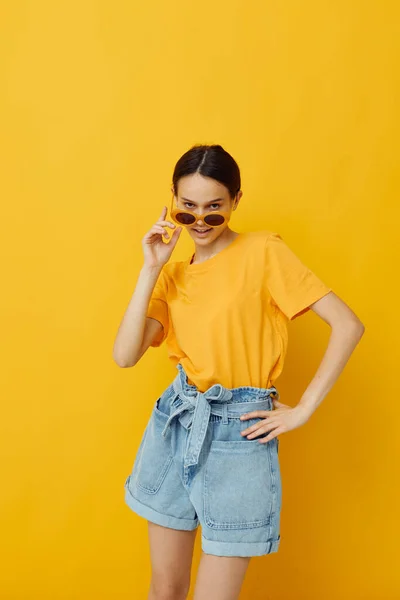 Photo pretty girl in a yellow hat Youth style casual wear in sunglasses yellow background — Stock Photo, Image