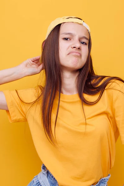 Jovem otimista posando em uma camiseta amarela e tampa de fundo amarelo — Fotografia de Stock