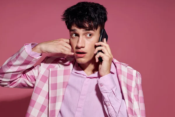 Retrato de un joven con un teléfono en la mano chaqueta rosa moda estilo elegante estilo de vida inalterado — Foto de Stock