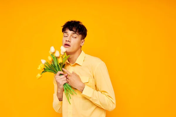 Bonito hombre dar flores desgaste gafas amarillo camisa aislado fondo inalterado — Foto de Stock