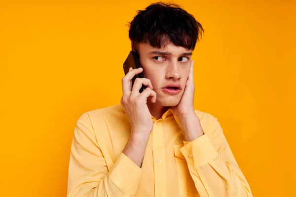 Un hombre guapo con una camisa amarilla hablando por teléfono de cerca — Foto de Stock