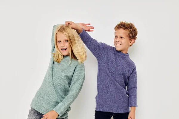 Foto di due bambini in maglioni multicolori in posa per divertimento sfondo luce — Foto Stock