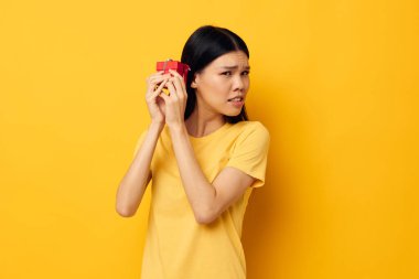 Güzel esmer kız elinde hediye kutusuyla yaşam tarzını değiştirmemiş gibi poz veriyor.