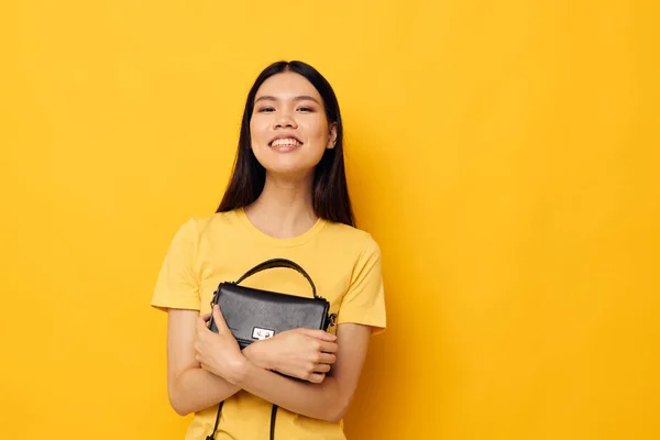 Söt asiatisk flicka poserar kvinnlig koppling väska gul bakgrund — Stockfoto