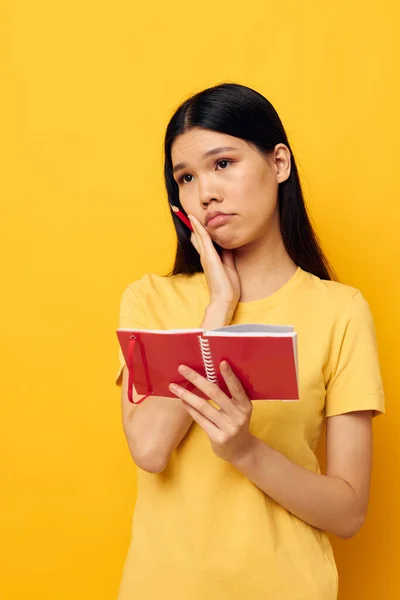 Jolie brune écrit dans un carnet avec un fond jaune crayon inchangé — Photo