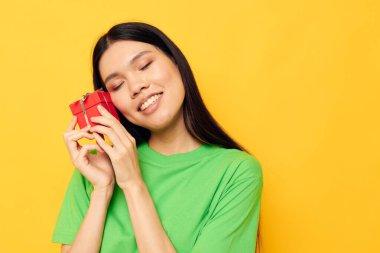 Yeşil tişörtlü güzel esmer, küçük hediye kutusu sarı arka planı değişmemiş.