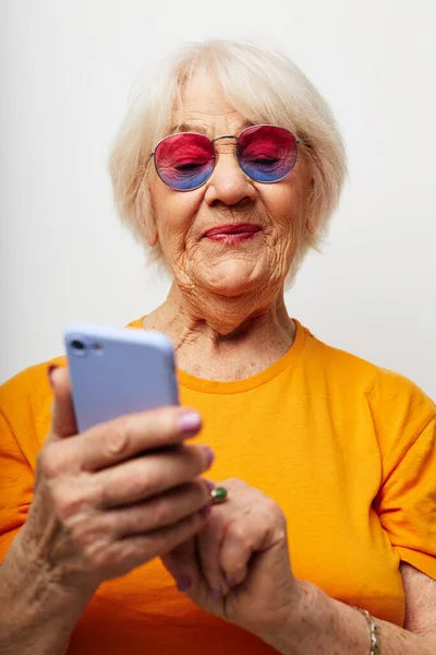 쉬지 않고 티셔츠에 선글라스를 끼고 통화하고 있는 은퇴 한 할머니의 사진 — 스톡 사진
