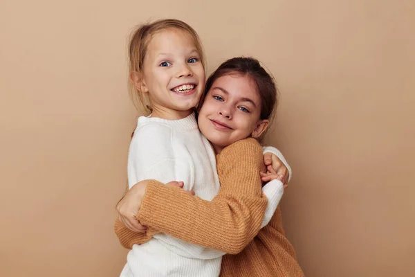 Дві смішні маленькі дівчата обіймають дружбу позує бежевий фон — стокове фото