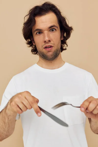 Man in a white T-shirt with knife with fork isolated background — Stok Foto