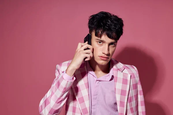 Chico guapo con un teléfono en la mano chaqueta rosa moda elegante estilo modelo estudio — Foto de Stock