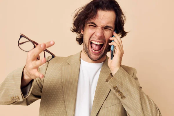 Veselý muž v obleku pózuje emoce mluví po telefonu béžové pozadí — Stock fotografie