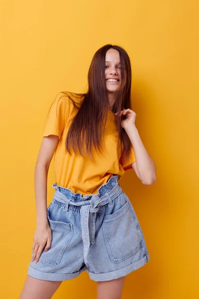 Optimistisk ung kvinna mode i gul t-shirt denim shorts isolerad bakgrund — Stockfoto