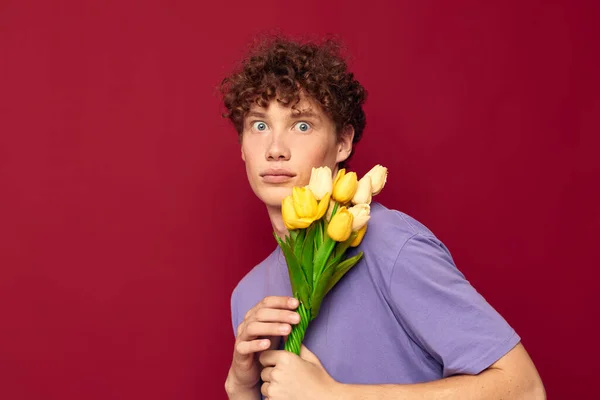 Дивний хлопець тримає жовтий букет квітів фіолетові футболки червоний фон незмінний — стокове фото