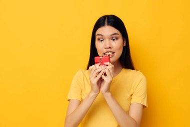 Güzel esmer kız elinde hediye kutusuyla yaşam tarzını değiştirmemiş gibi poz veriyor.