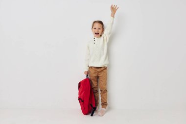 Güzel genç kız kırmızı sırt çantası şık kıyafetler izole edilmiş arka plan.