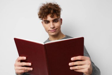 Kıvırcık saçlı, elinde kitap olan yakışıklı bir adam.