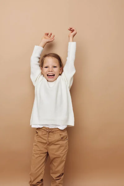 Портрет счастливой улыбающейся девочки в белом свитере, изображающей жесты рук — стоковое фото