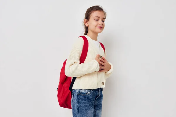 Pequena estudante com mochila vermelha posando fundo isolado — Fotografia de Stock