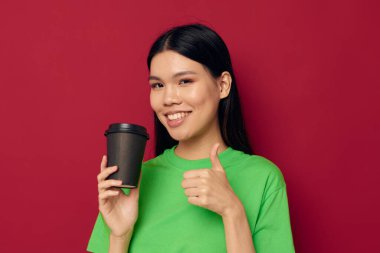 Çekici genç Asyalı kadın yeşil tişörtlü, tek kullanımlık siyah gözlüklü stüdyo modeli ile poz veriyor.