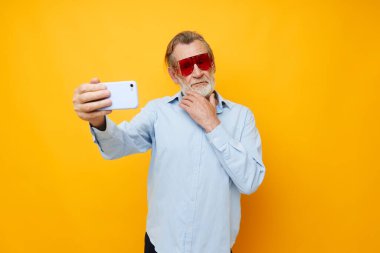 Yaşlı bir adamın portresi mavi gömlekli ve gözlüklü bir selfie çekiyor.