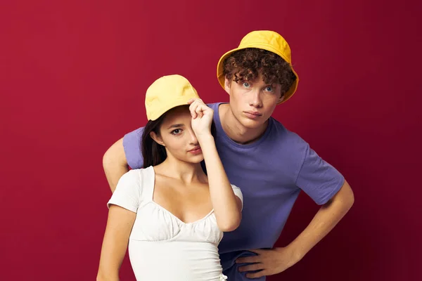 Jonge man en meisje in gele hoeden poseren samen vriendschap geïsoleerde achtergrond — Stockfoto