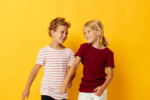 two joyful children cuddling fashion childhood entertainment yellow background