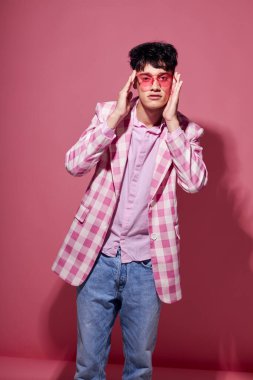 Genç bir adam ekose ceketli pembe gözlükler modern moda pembe arka plan değiştirilmemiş