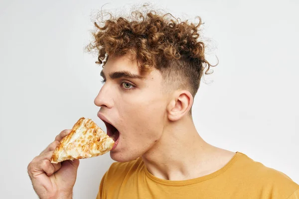 魅力的な男食べるピザポーズクローズアップライフスタイル変更なし — ストック写真