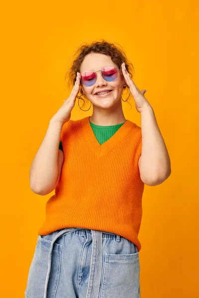 Beautiful woman orange sweatshirts sunglasses multicolored glasses supply yellow background unaltered — Stock Photo, Image