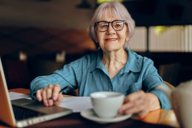 Yaşlı kadın kâğıt ve kalem kağıtlarını belgeledi. Emekli kadın, değişmeden sohbet ediyor.