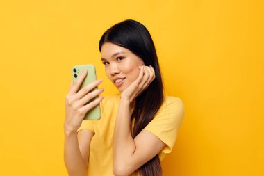 Elinde telefon olan güzel bir esmer, özçekim yapıyor. Değiştirilmemiş bir arka plan.