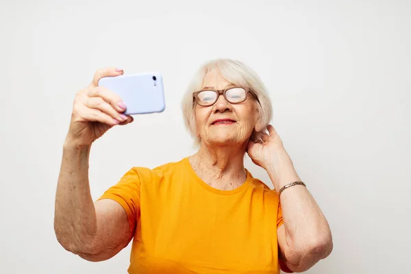 노란 티셔츠를 입고 전화기등을 켜고 의사소통을 하는 노인 — 스톡 사진