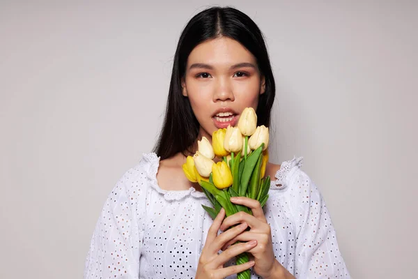 젊은 아시아 여성에게 꽃 다발을 선물하는 장면은 아무런 변화 없이 고립된 배경에 미소를 짓고 있다 — 스톡 사진