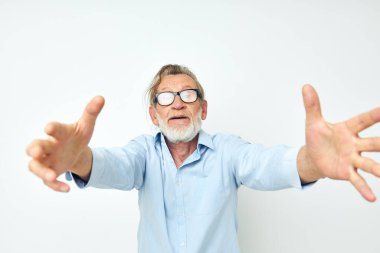 Mavi gömlekli yaşlı adam, elleri izole edilmiş bir şekilde el kol hareketi yapar.