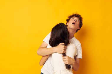 Tatlı, genç bir çift beyaz tişörtlerle birbirlerine sarılıyorlar. Arka planda bir değişiklik yok.