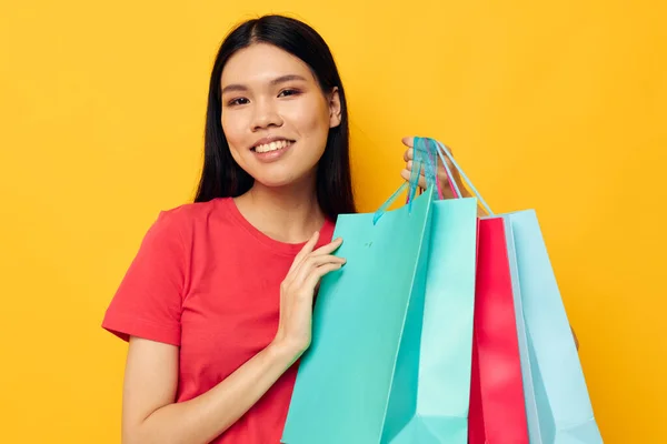Portrait Asian beautiful young woman with multicolored shopping bags yellow background unaltered — Stock Photo, Image