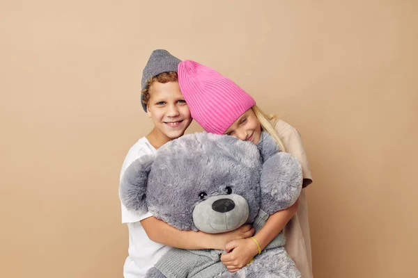 Portrait of cute children in hats with a teddy bear friendship isolated background — 图库照片