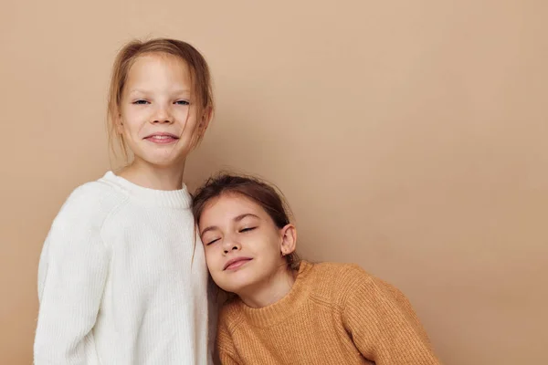 Two cute little girls hug friendship beige background — 图库照片