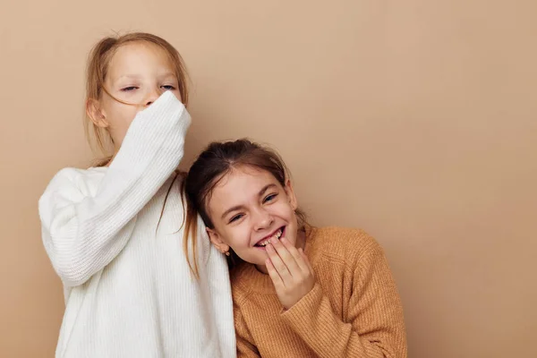 Two cute little girls hug friendship beige background — стоковое фото
