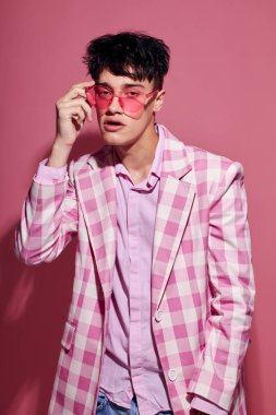 Pembe gözlüklü yakışıklı adam stüdyoda poz veriyor. Arka planda değişiklik yok.