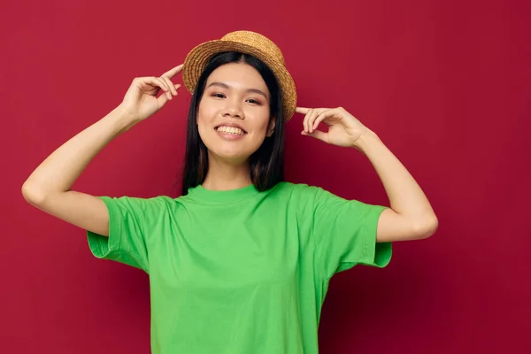 아무런 변화 없이 그린 티셔츠를 입고 손으로 모자를 쓰고 아시아의 모습을 하고 있는 여성 — 스톡 사진