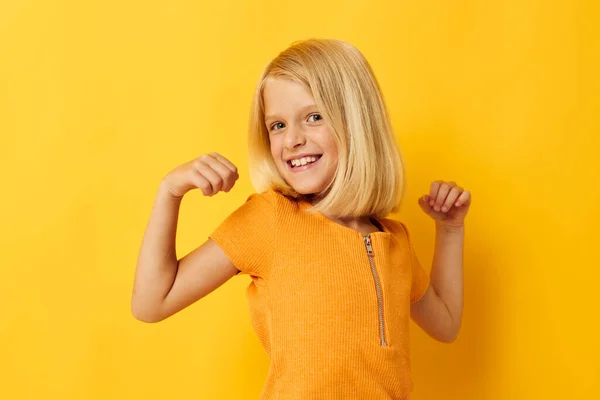 Sarı tişörtlü küçük kız gülümsüyor. Stüdyoda çocukluk hayatı pozu veriyor. — Stok fotoğraf