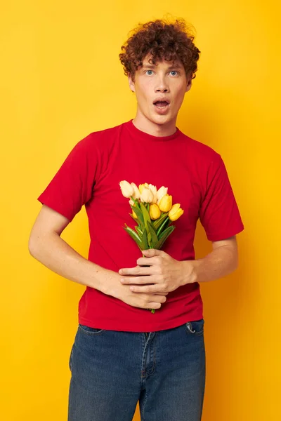 Porträtt av en ung lockig man romantisk poserar med en gul bukett blommor gul bakgrund oförändrad — Stockfoto
